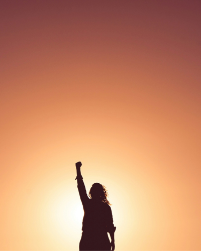 lady with pumping fist in the sunrise background