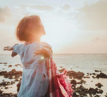 girl with open arms infront of ocean